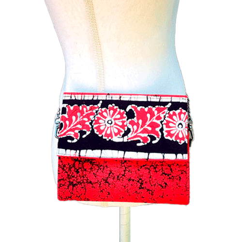 A flat handbag with a flap made of black, white, and red batik cotton fabric.