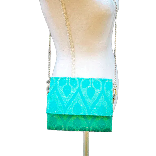 A flat handbag with a flap made from cream and turquoise babywearing wrap with stylized leaf pattern.