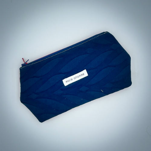 A double zippered pouch sewn from several babywearing wrap scraps (blue and red) and white faux leather.