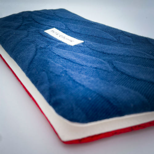 A double zippered pouch sewn from several babywearing wrap scraps (blue and red) and white faux leather.