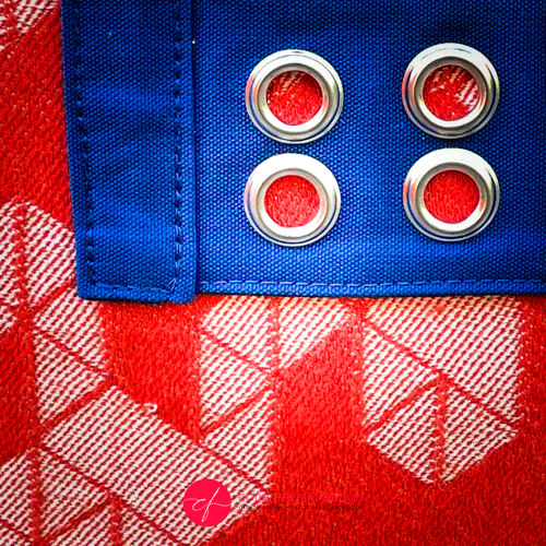 A mini handbag made of orange babywearing wrap fabric with a white geometric pattern, and blue Klein workwear fabric.
