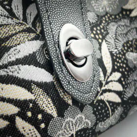 A mini handbag made of black, white, gray, and gold upholstery fabric, combined with anthracite and silver leather.