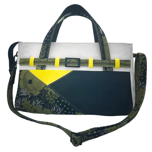 A long, low bag made from yellow, white and black leather and a wrap fabric with a floral pattern in black, yellow and white, lined with yellow canvas.