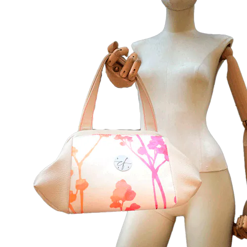 A handbag made of cream synthetic upholstery fabric and cream faux leather, featuring a gradient botanical pattern from pink to orange.