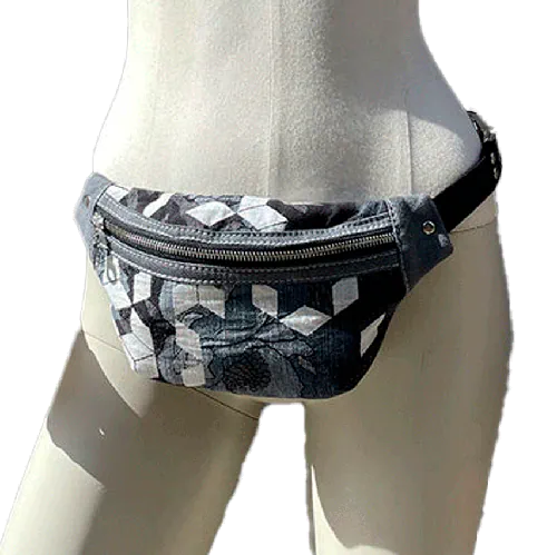 A fanny pack made from babywearing fabric in gray, white, and blue tones with a floral and geometric pattern and gray denim.