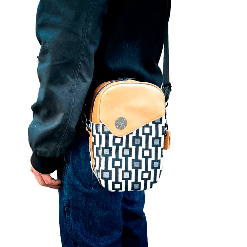 A messenger bag made from a black and white geometric pattern babywearing wrap, caramel leather, and red poplin.
