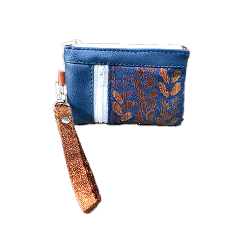 A mini zippered coin purse made up of a patchwork of different materials: royal blue faux leather, golden faux leather, shiny bronze fabric, and blue and bronze wrap fabric with a pattern of small droplets.