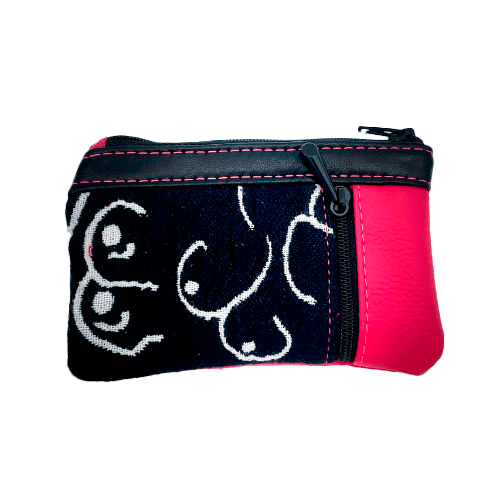 A mini zippered coin purse made from a patchwork of different materials: black and white babywearing wrap with stylized breast pattern, black lambskin leather, and fuchsia pink faux leather.