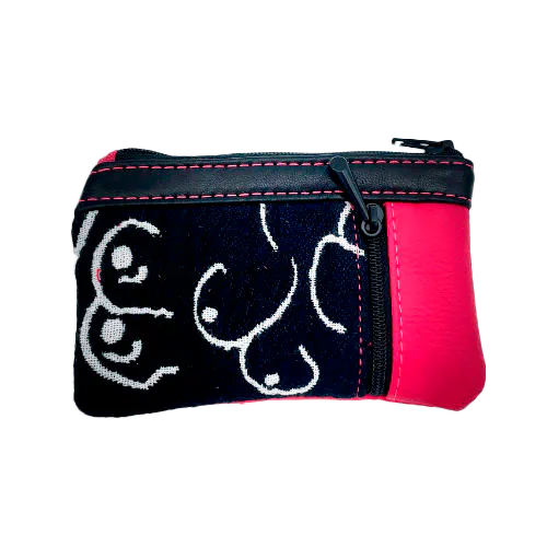 A mini zippered coin purse made from a patchwork of different materials: black and white babywearing wrap with stylized breast pattern, black lambskin leather, and fuchsia pink faux leather.