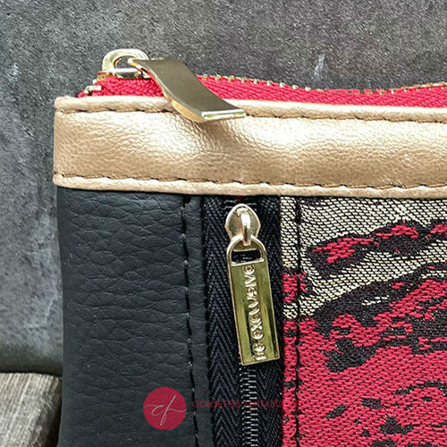 A mini zippered coin purse made from black, gold, and red faux leather and a wrap fabric in matching tones with a marbled pattern.