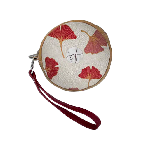 A round pouch made of camel colored leather and a red Ginkgo Biloba leaves patterned polycotton canvas.