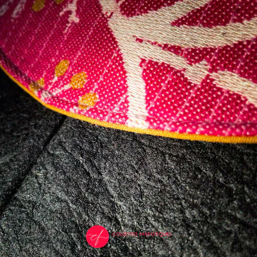 A small pouch made of pineapple-based faux leather in black and a pink, white, and yellow wrap fabric.