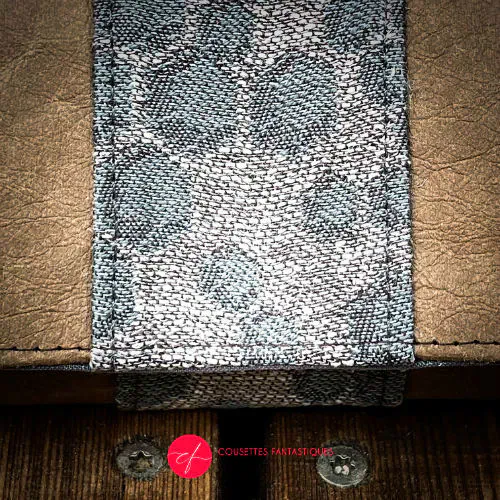 A wallet made of brown washable paper and a gray babywearing wrap with a hive pattern.