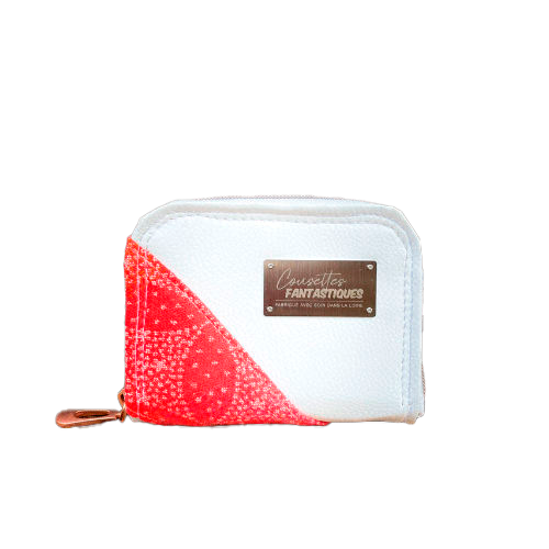 A small zippered card and coin holder made with gradient wrap fabric from orange-yellow to pink, with a pointillist star pattern, and white faux leather.