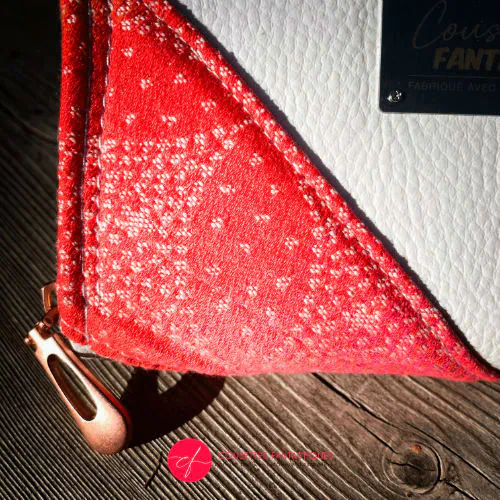 A small zippered card and coin holder made with gradient wrap fabric from orange-yellow to pink, with a pointillist star pattern, and white faux leather.