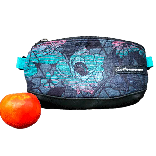 A small zippered clutch sewn in black cork and a babywearing wrap with geometric and floral patterns in shades of blue, green, and pink.