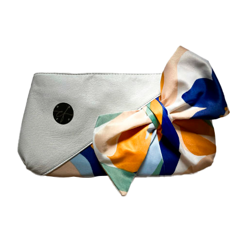 A small zippered pouch sewn in white faux leather and a colorful neck scarf with an abstract and modern flowery design in white, blue, sage, beige and cinammon. Inside is a light sage shiny poplin.