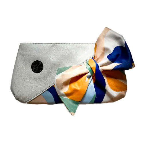 A small zippered pouch sewn in white faux leather and a colorful neck scarf with an abstract and modern flowery design in white, blue, sage, beige and cinammon. Inside is a light sage shiny poplin.