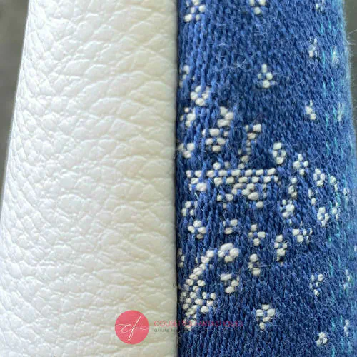 A small zippered pouch made of blue and white babywearing wrap with pointillist star motif and white faux leather.