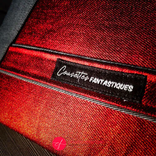 A zippered pouch sewn in gray reversible denim and metallic red, combined with bright red silk.