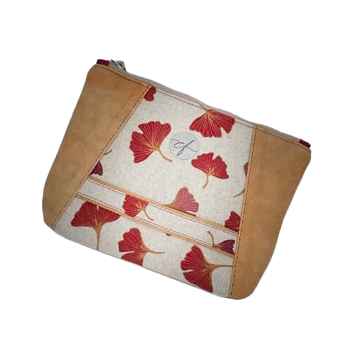 A zippered pouch sewn from a camel colored leather and a red Ginkgo Biloba leaves patterned polycotton canvas.