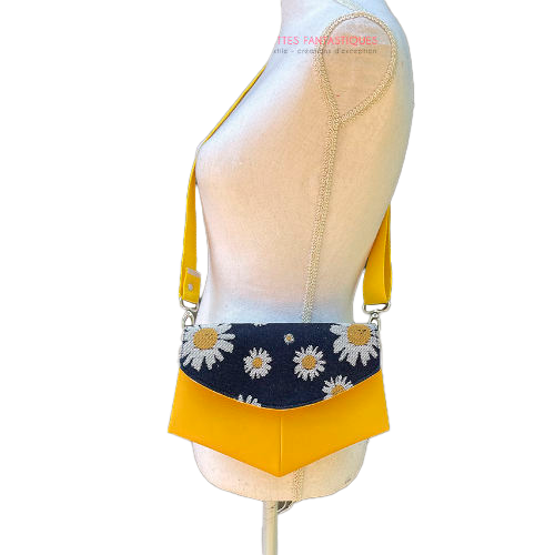 A small bag made from yellow faux leather and a fabric coupon with white and yellow daisies on a navy blue background.