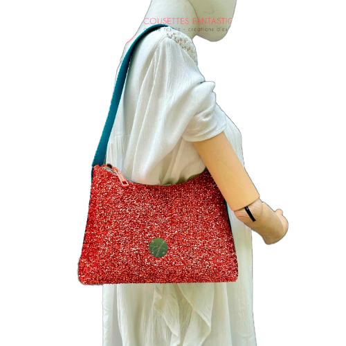 A zippered small shoulder bag made from stretch fabric with copper metallic bouclé, turquoise blue faux leather, and bright light orange lining.