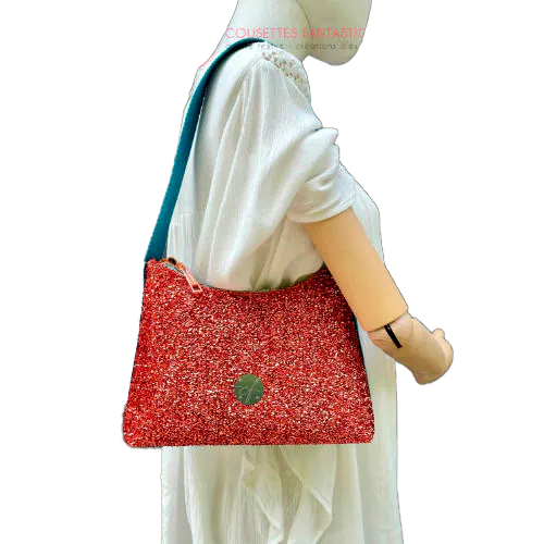 A zippered small shoulder bag made from stretch fabric with copper metallic bouclé, turquoise blue faux leather, and bright light orange lining.