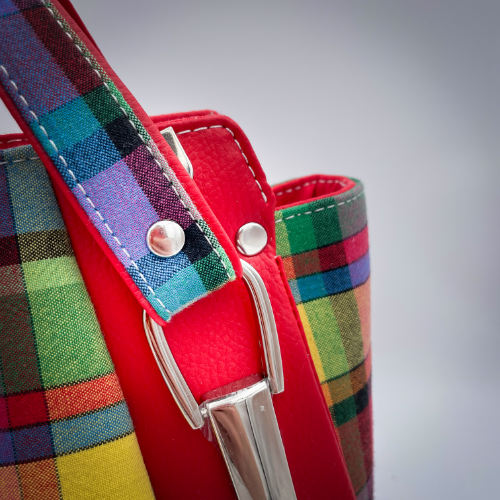 A shoulder bag made of blood-red faux leather and multicolored madras fabric.