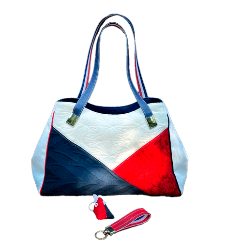 A shoulder bag made with several babywearing wrap coupons (blue, white, and red) and white and blue faux leather.
