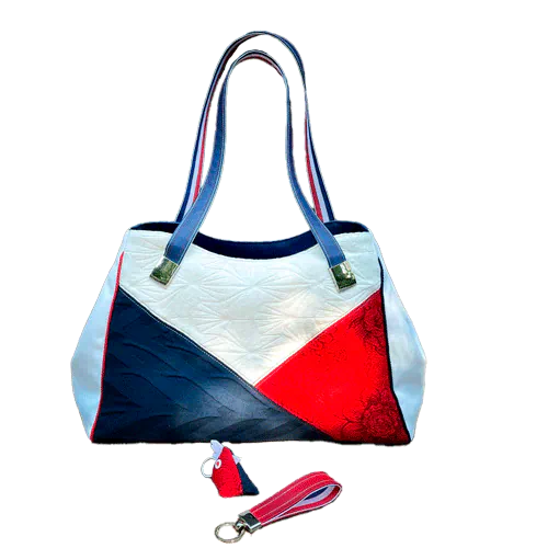 A shoulder bag made with several babywearing wrap coupons (blue, white, and red) and white and blue faux leather.