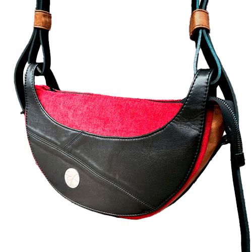 A shoulder bag made of black and caramel leathers, red and black velvet upholstery fabric, and red and black satins.