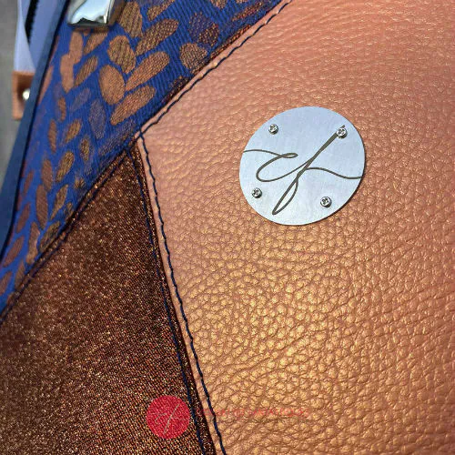 A shoulder bag made up of a patchwork of different materials: royal blue faux leather, golden faux leather, shiny bronze fabric, and blue and bronze wrap fabric with a pattern of small droplets.