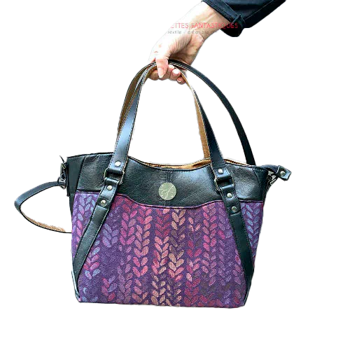A shoulder bag made from fabric in purples, purples, pinks... with droplet motifs, and upcycled black lamb leather.