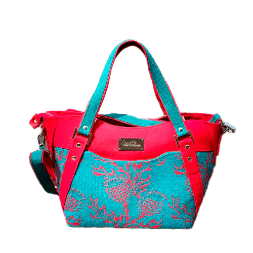 A shoulder bag made from blood red and emerald green babywearing wrap with a thistle pattern, red gabardine, emerald green linen, and synthetic material.