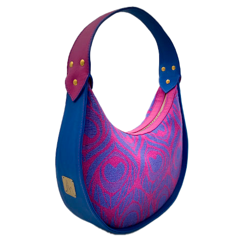 A shoulder bag made from royal blue and bright pink leathers, combined with a pink and blue baby wrap fabric featuring stylized peacock feather motifs.