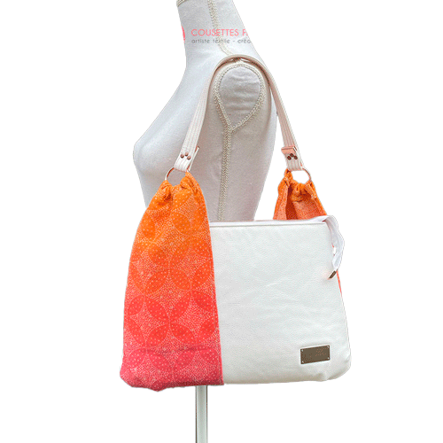 A shoulder bag made from babywearing wrap with a gradient from orange-yellow to pink, with a pointillist star pattern, and white synthetic leather.