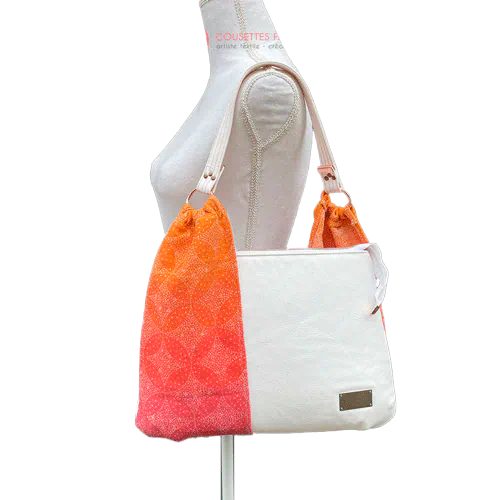 A shoulder bag made from babywearing wrap with a gradient from orange-yellow to pink, with a pointillist star pattern, and white synthetic leather.