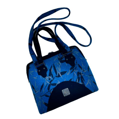 A shoulder bag made from baby wrap fabric featuring a black and royal blue bamboo pattern, paired with boiled black wool and glittered textured leather, complemented by a blue-gray satin lining.