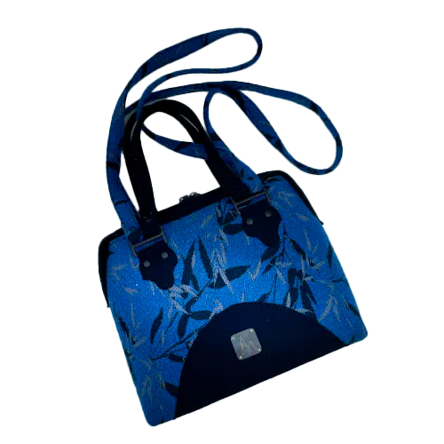 A shoulder bag made from baby wrap fabric featuring a black and royal blue bamboo pattern, paired with boiled black wool and glittered textured leather, complemented by a blue-gray satin lining.