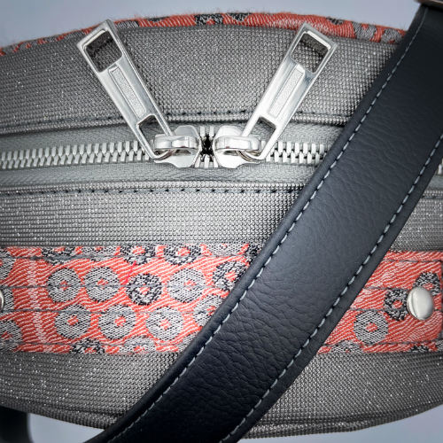 A round shoulder bag made of gray glitter vinyl canvas, with a vintage floral patterned pink and gray baby sling scrap and a gray satin lining.