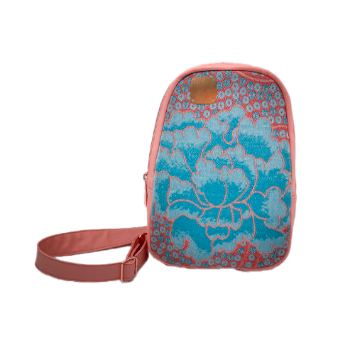 A backpack made of peach-colored faux leather and a babywearing wrap in shades of pink and turquoise with a vintage floral pattern.