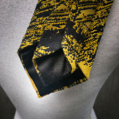 A tie made from black and gold woven wrap, marbled pattern.