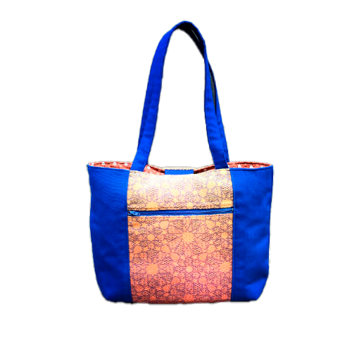A tote bag made from royal blue fabric, a babywearing wrap with an Arabesque geometric pattern in blue on a gradient background from orange to yellow, and orange cretonne with geometric patterns.