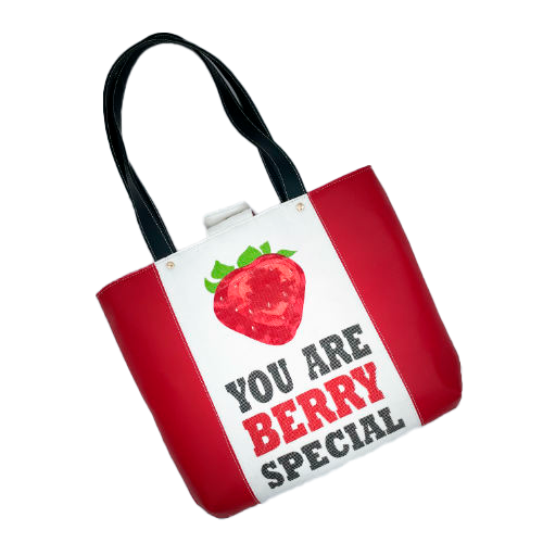 A large bag made from red faux leather on the outside and a canvas printed with a fruit design with an English pun underneath, and on the inside a bright red poplin.