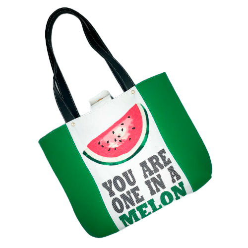 A large bag made from green leather on the outside and a canvas printed with a fruit design with an English pun underneath, and on the inside a forest green poplin.