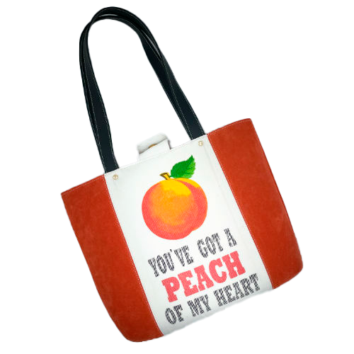 A large bag made from orange leather on the outside and a canvas printed with a fruit design and English wordplay underneath, with an iridescent orange viscose interior.
