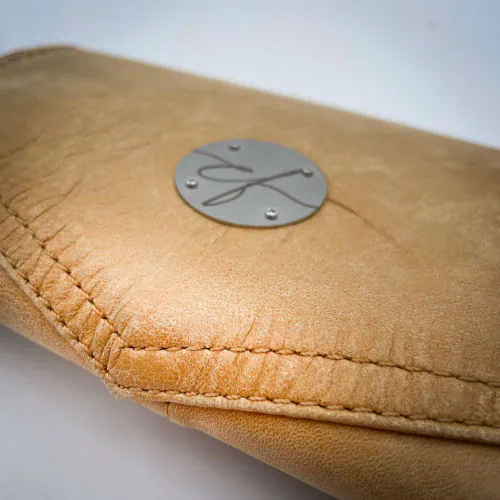 A wallet made from camel colored leather and a red Ginkgo Biloba leaves patterned polycotton canvas.