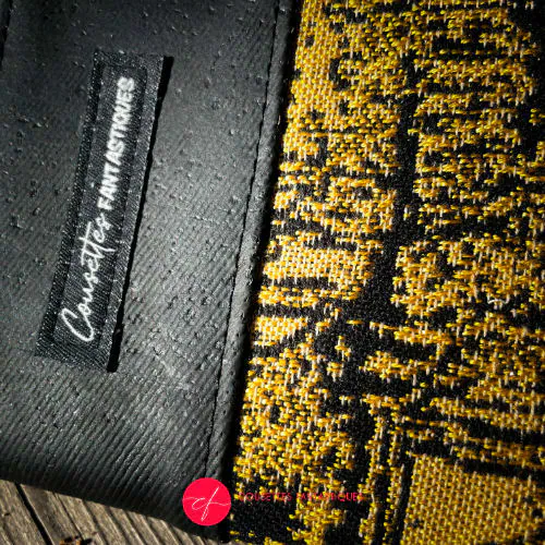 A zippered card and coin holder made with black and gold marbled babywearing wrap fabric and matte black cork.