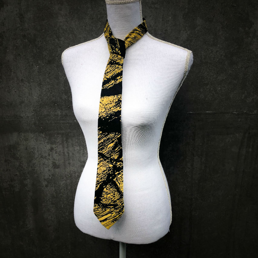 A tie made from black and gold woven wrap, marbled pattern.